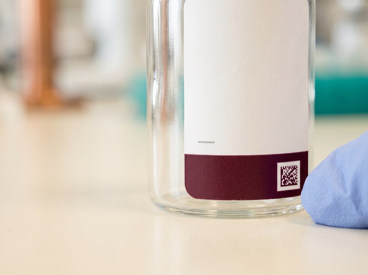 Close-up of a vial label with its printed code, on a lab bench.